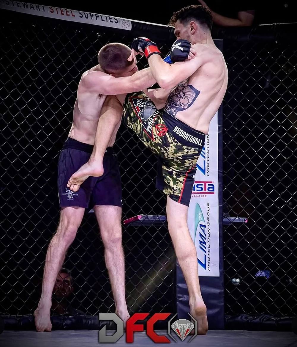A Born To Roll fighter landing a knee in the cage at DFC